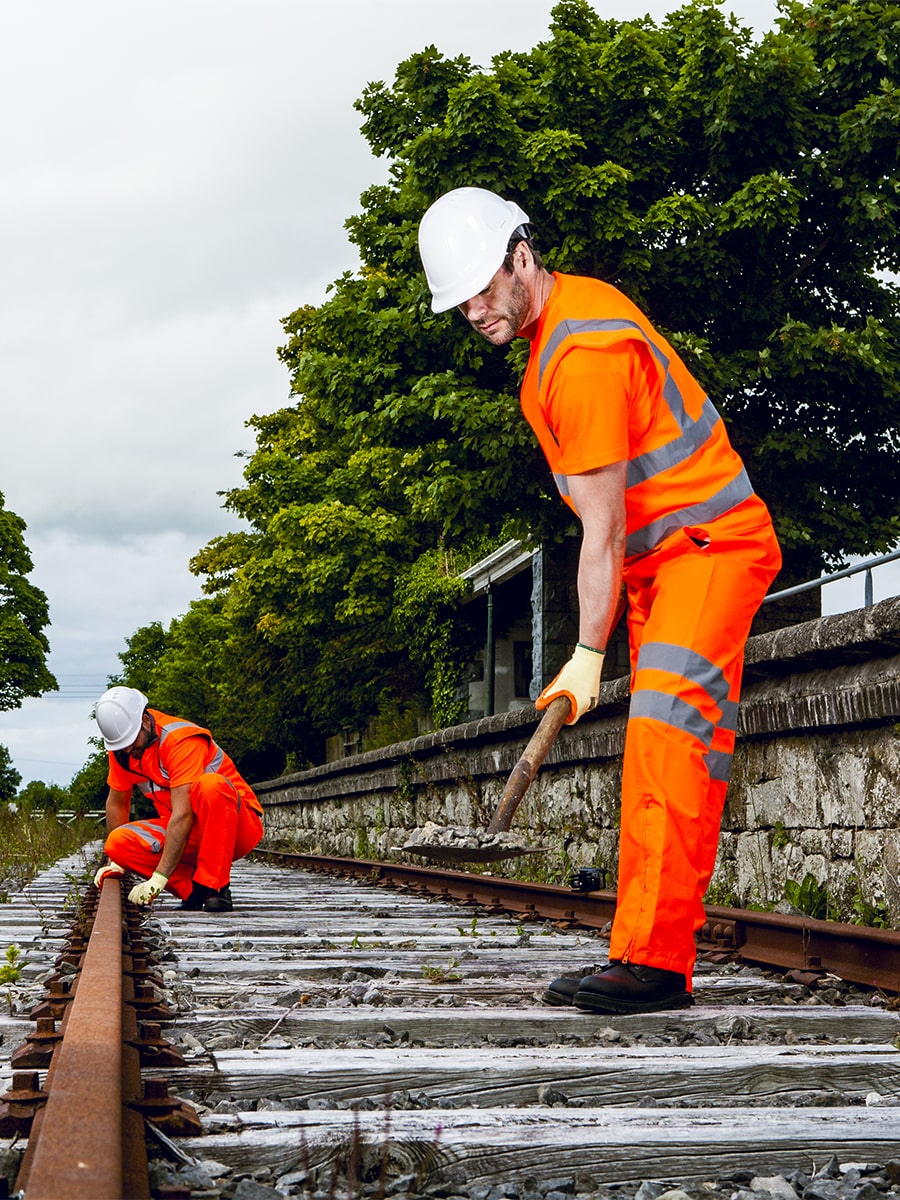 Portwest Warnschutzweste am Bauarbeiter, orange mit Reflexstreifen über Brust und Rücken